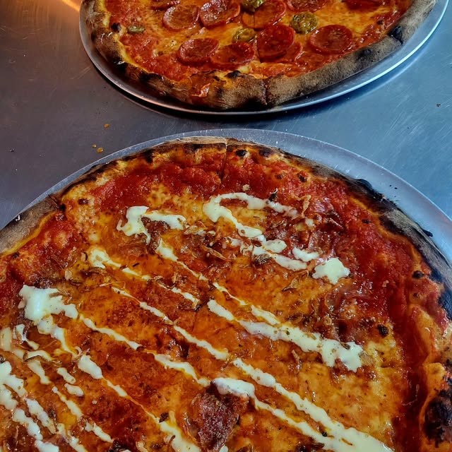 Two New York style pizzas, one with garlic drizzle